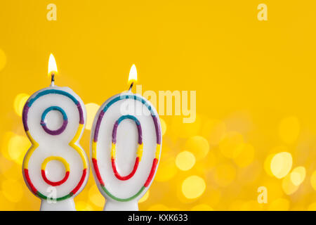 Nummer 80 Geburtstag Kerze gegen eine helle Lichter und gelbem Hintergrund Stockfoto