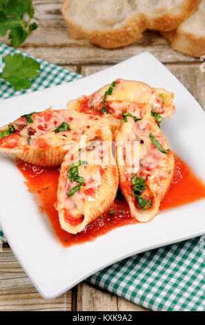 Pasta conchiglioni Schalen, gefüllt mit Fleisch mit Spinat und Tomatensauce Hackfleisch, Parmesan, auf einer Platte. Stockfoto