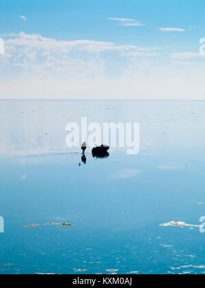 Djerba, Tunesien, Fischer, Spaziergänge im Meer zu seinem eigenen Boot im blauen Wasser spiegelt Stockfoto