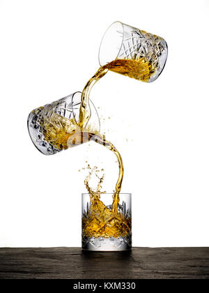 Zwei Gläser Whisky taumeln und Mischung in ein drittes Glas. Stockfoto