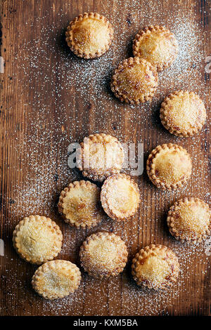 Frisch gebackene Torten mince, bestäubt mit Zucker, auf Holz- zähler, Ansicht von oben Stockfoto