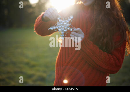 Junge Frau in ländlicher Umgebung, Weihnachtsstern, mittlere Partie Stockfoto