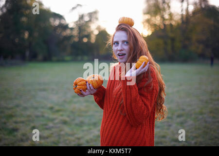 Junge Frau in ländlicher Umgebung, Kürbis, Kürbis in Kopf ausgeglichen Stockfoto