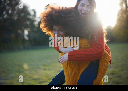 Zwei junge Frauen, die in der ländlichen Umgebung, junge Frau, Freund piggyback Ride