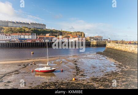 Whitby. Boot um bei Ebbe mit Stadt im Hintergrund und einem blauen Himmel. Stockfoto