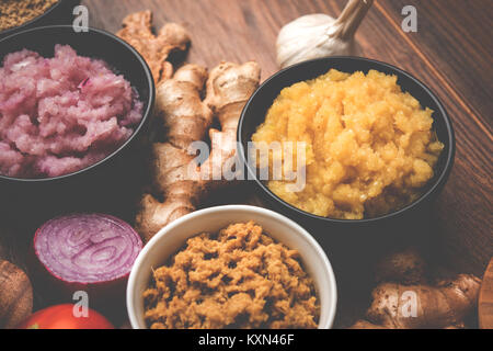 Ingwer, Knoblauch, Zwiebel und Tomatenmark und Pulver in und rohen Form. Gruppe von grundlegenden indischen Lebensmittelzutaten über Holz- Hintergrund. Selektiver Fokus Stockfoto