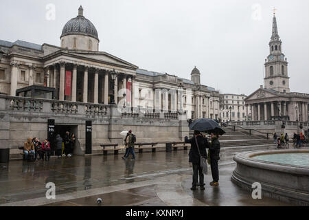 London, Großbritannien. 11 Jan, 2018. Leute, Sonnenschirme, Spaziergang im Regen auf dem Trafalgar Square. Credit: Mark Kerrison/Alamy leben Nachrichten Stockfoto