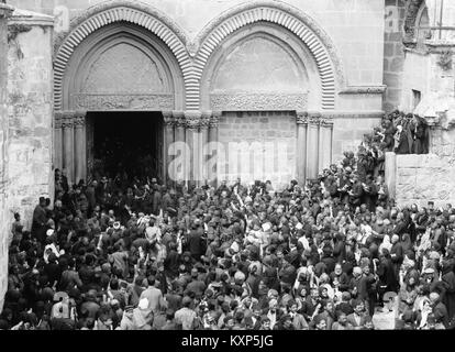 Dieses Bild zeigt Menschenmassen vor der Grabeskirche in Jerusalem, die auf das Heilige Feuer warteten, ein jährliches christliches Ereignis, während des frühen 20. Jahrhunderts. Stockfoto