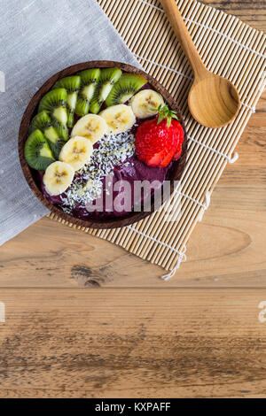 Acai Schüssel mit Serviette und Löffel - Schüssel der acai Püree mit Belag aus Banane, Kiwi, Erdbeeren und Samen. Stockfoto