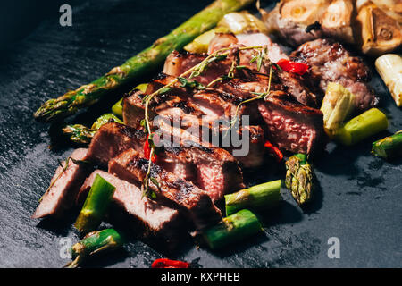 Nahaufnahme der Gourmet Geschnetzeltes Fleisch vom Grill mit Spargel und Gewürzen auf Schwarz Stockfoto
