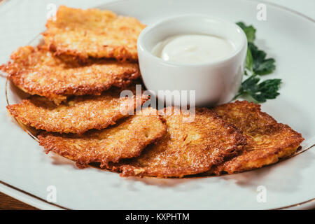 Nahaufnahme der Kartoffelpfannkuchen serviert mit saurer Sahne Soße auf Platte Stockfoto