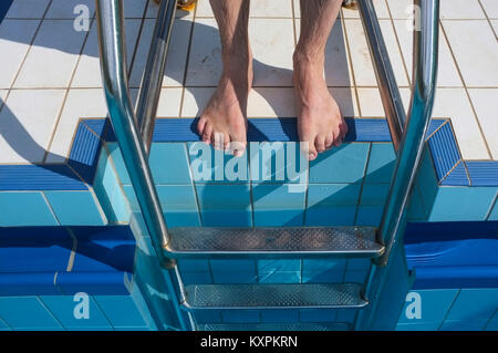 Die Füße des Menschen an der Spitze eines Schwimmbad Leiter. Stockfoto