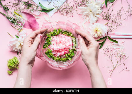 Rosa Florist Arbeitsbereich mit Rosen und anderen Blumen, Glas Vase mit Wasser. Weibliche Hände, festliche Blumen Arrangements, Ansicht von oben Stockfoto