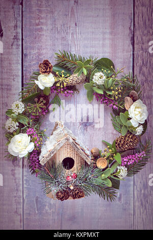 Nahaufnahme einer festlichen, Weihnachten Tür Kranz mit kleinen Vogel Haus verbunden. Stockfoto