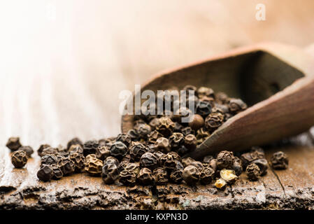 Holz- Schaufel mit schwarzem Pfeffer auf dem Tisch Stockfoto