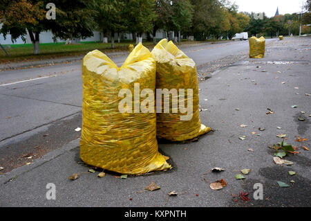 Reinigung der Straßen im Herbst, Gelbe Müllsäcke mit Laub gefüllt Stockfoto