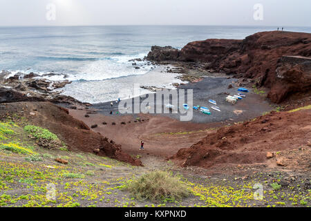 Wilden Strand am Atlantischen Ozean in El Golfo Dorf. Ein felsiger Strand mit Fischerbooten von vulkanischen Bergen umgeben Stockfoto