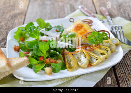 Gebratene schwäbische Fleisch Ravioli (so 'Maultaschen' genannt) serviert mit Feldsalat mit Croutons, Speck und Parmesan Stockfoto