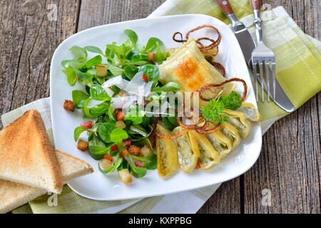 Gebratene schwäbische Fleisch Ravioli (so 'Maultaschen' genannt) serviert mit Feldsalat mit Croutons, Speck und Parmesan Stockfoto