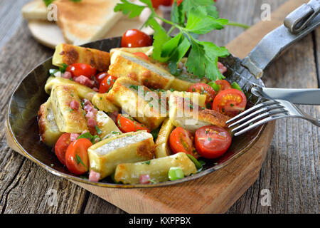 Gebratene schwäbische Fleisch Ravioli (so genannte 'Maultaschen') mit Speck und gebratenen Kirschtomaten in eine eiserne Pfanne serviert pan Stockfoto