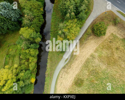 Abstrakte Luftaufnahme von eine aufgebogene Stream neben einer Wiese mit einem großen, abgelegenen Grüner Baum, von Drone gemacht Stockfoto