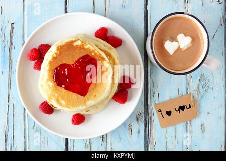 Pfannkuchen mit Marmelade in Form von Herzen, heiße Schokolade und ich liebe Sie Tag über einem blauen Holz Tisch git. Liebe Konzept. Stockfoto