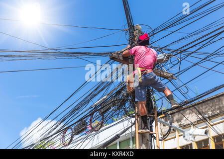 Keine Sicherheit der Arbeitnehmer Techniker installieren Internet Kabel auf den Strommasten in asiatischen Land Stockfoto