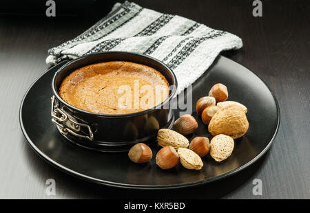 Hausgemachte Schokolade Käsekuchen in kleinen Springform geben auf schwarze Platte mit Nüsse auf dem Tisch. Stockfoto