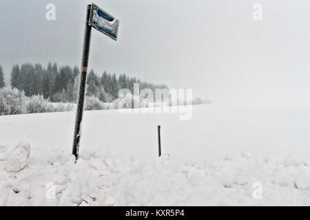 Die Bushaltestelle Zeichen ist mit Frost und Eis an einem kalten Tag im ländlichen Finnland abgedeckt. Den schweren Schnee hat fast die Bushaltestelle blockiert. Stockfoto