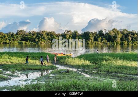 Unbekannte Kinder spielen am Ufer des Flusses, in der Nähe des Dorfes. Rückgang, am Ende des Tages. Juni 26, 2012 in Dorf, Neuguinea, Indonesien Stockfoto