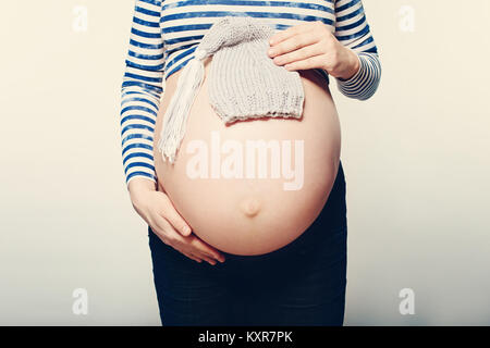 Schwangere Mutter. Weibliche Bauch und kleinen Baby Hut auf Hintergrund Stockfoto