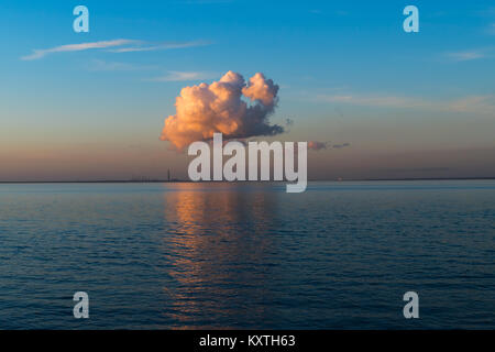 Einzige Wolke spiegelt das rote Glühen des Sonnenuntergangs. Die Cloud ist auch in den Solent, Ryde, Isle of Wight wider, mit einem weit entfernten Blick auf Fawley Stockfoto