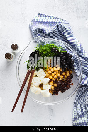 Gesund vegan Mittagessen Schüssel. Kichererbsen, Tomaten, Feta Käse oder Tofu, Rucola und schwarzen Oliven gemüse salat getrocknet. Ansicht von oben Stockfoto