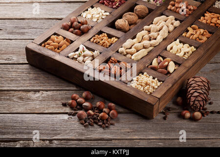 Verschiedene Nüsse: Erdnüsse, Haselnüsse, Walnüsse, Esskastanien, Pistazien und Pekannüssen in Holzkiste Stockfoto