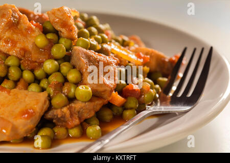 Eintopf mit Erbsen, Schweinefleisch, Karotten, Zwiebeln, Tomatensauce und Gewürze Stockfoto