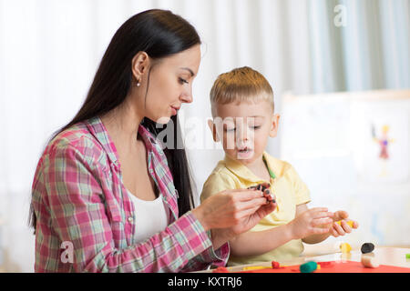 Kind Junge und junge Frau spielen bunt Ton Spielzeug im Kindergarten oder in den Kindergarten Stockfoto