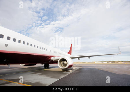 Zugeschnittenes Bild von stationären Commercial Airplane auf Startbahn gegen bewölkter Himmel Stockfoto