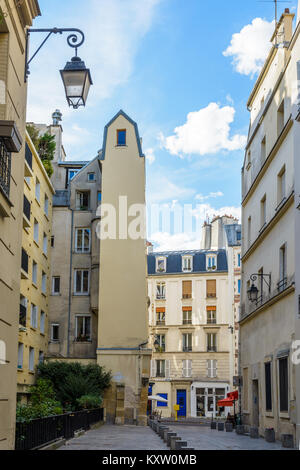 Ein schmales Gebäude in einer kleinen Fußgängerzone im historischen Zentrum von Paris mit Vintage Straßenlaternen unter einem blauen Himmel. Stockfoto