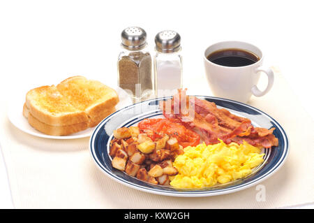 Blaue platte Frühstück mit Rührei, Hash Brown Kartoffeln, Streifen von Speck, gegrillten Tomaten, Gebutterte weißen Toast, Tasse schwarzen Kaffee Stockfoto