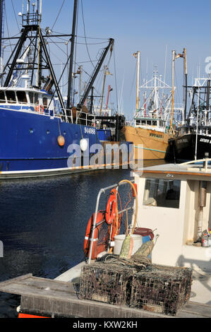 Stahl geschält Fischtrawler gebunden im Hintergrund mit Lobster Boat im Vordergrund in New Bedford Hafen zur Wharf, Massachusetts, USA Stockfoto
