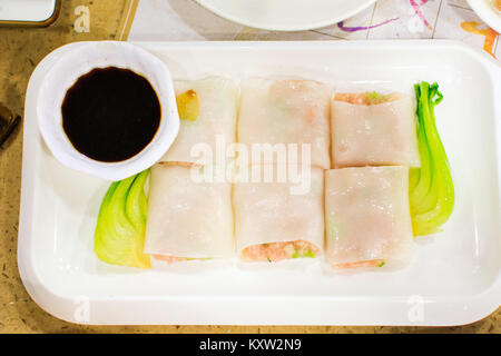 Dampf Reis Nudeln Rollen gefüllt mit Schweinefleisch und Gemüse auf weißen Teller am Tisch serviert Stockfoto