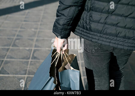 Nahaufnahme eines jungen kaukasischen Mann von hinten mit etwas Papier Einkaufstüten mit seiner Einkäufe auf der Straße aus gesehen Stockfoto