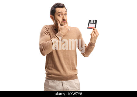 Junger Mann mit einer Diskette auf weißem Hintergrund verwirrt Stockfoto
