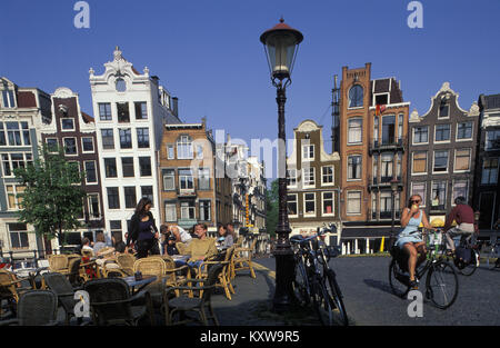 Die Niederlande, Amsterdam, Kanal namens Singel. UNESCO-Weltkulturerbe. Menschen sitzen auf der Terrasse des Café im Freien. Radfahrer. 17. Jahrhundert. Stockfoto