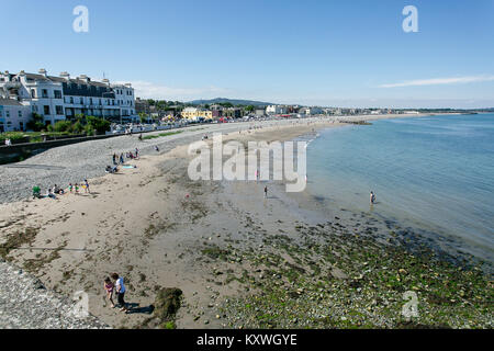 Leute genießen gutes Wetter sonnen, während die Kinder im Wasser spielen bei der Bray direkt am Meer an einem sonnigen Sommertag. County Wicklow, Irland Stockfoto