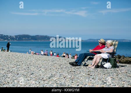 Ältere Paare Mann und Frau Entspannung an einem sonnigen Sommertag auf einem Stein Strand in Bray, County Wicklow, Irland Stockfoto