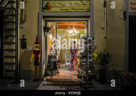 Eine übergroße Pinocchio marionette Marionette außerhalb ein Geschenk und Souvenir Shop in Pisa, Italien in den späten Abend mit einem Kunden innerhalb Stockfoto