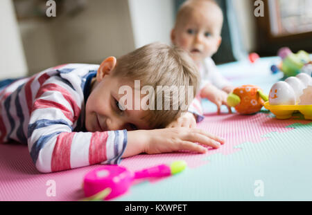 Süße kleine Kinder spielen beim Sitzen auf dem Teppich Stockfoto