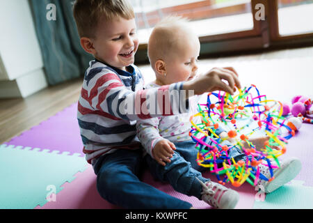 Süße kleine Kinder spielen beim Sitzen auf dem Teppich Stockfoto