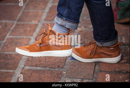 In der Nähe des Mann Füße tragen moderne und trendige braune Schuhe und rollte Jeans Stockfoto